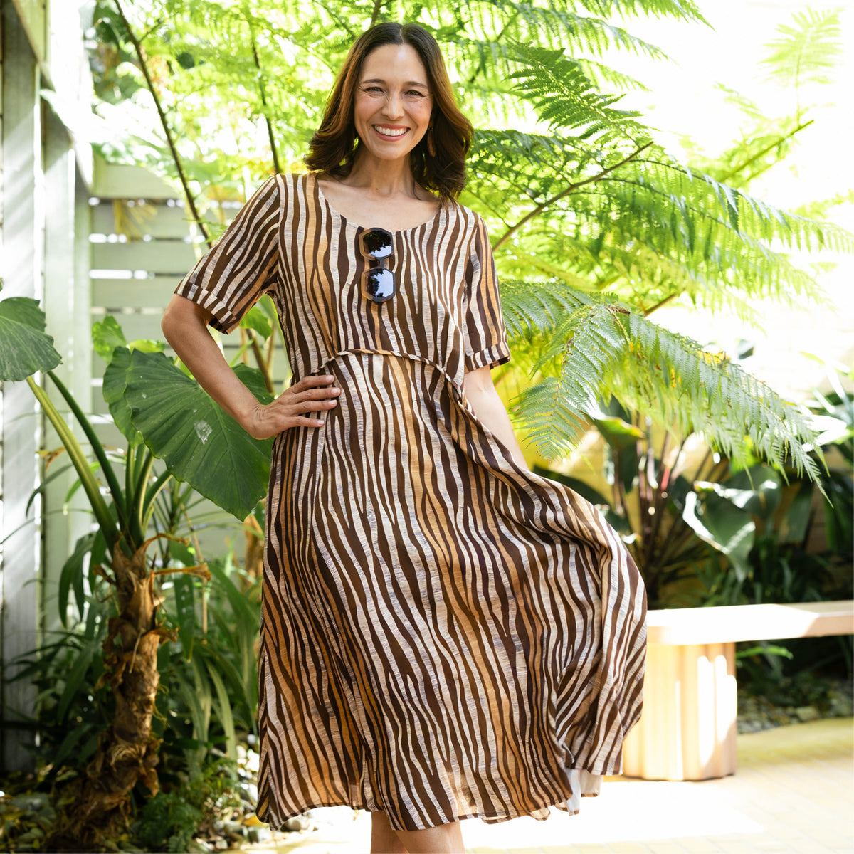 Brunette woman in a brown animal-inspired stripe print A-line dress with flattering curved crescent waist