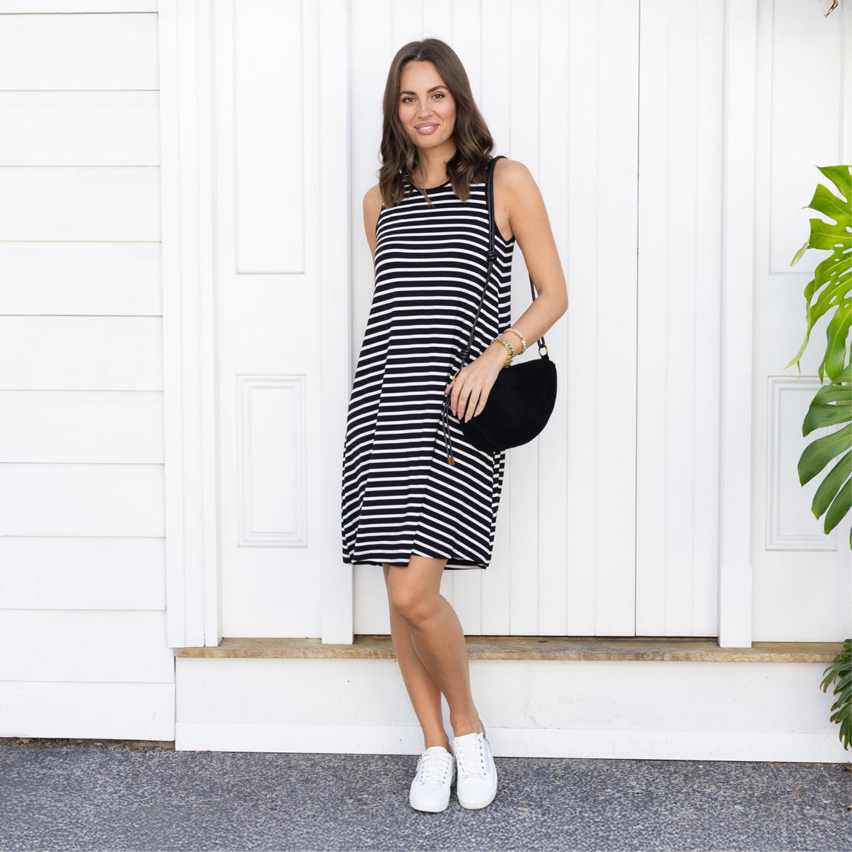 Brunette woman in a sleeveless striped casual dress above the knee