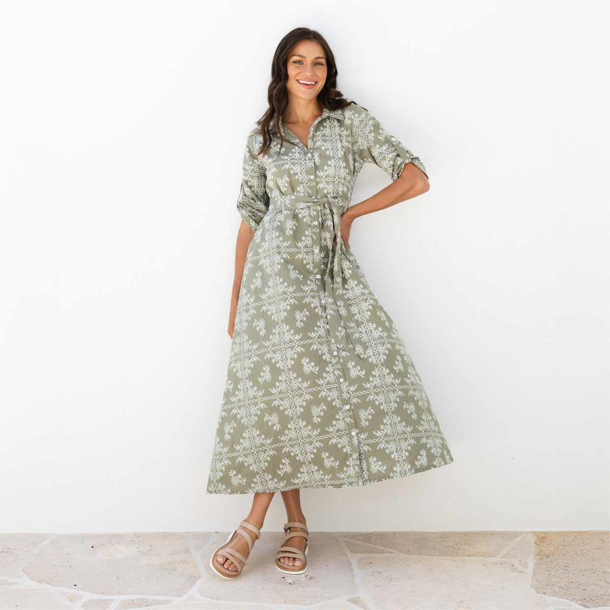 Brunette woman in a long sage green and white sleeved belted shirt dress