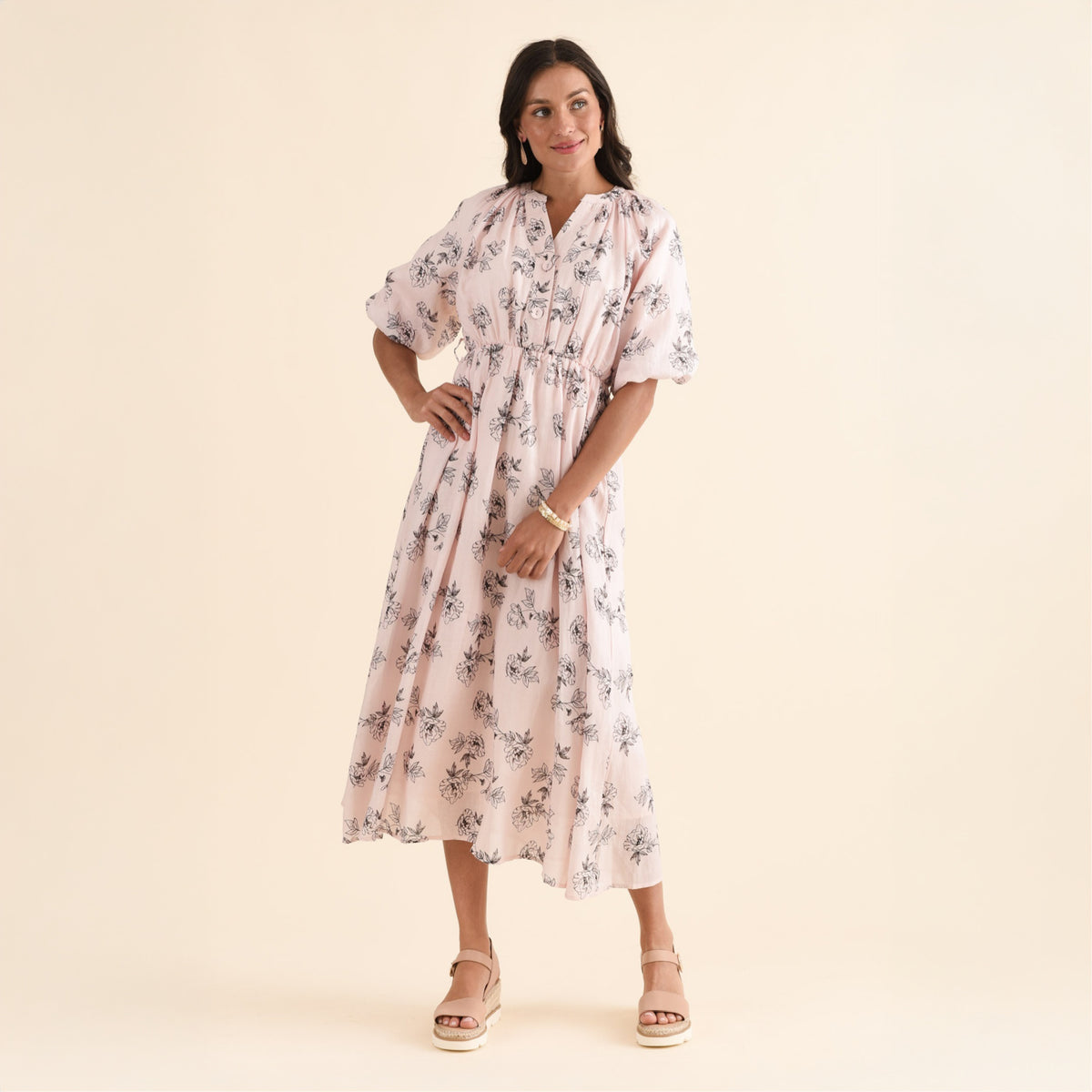Brunette woman in a printed blush linen dress below the knee