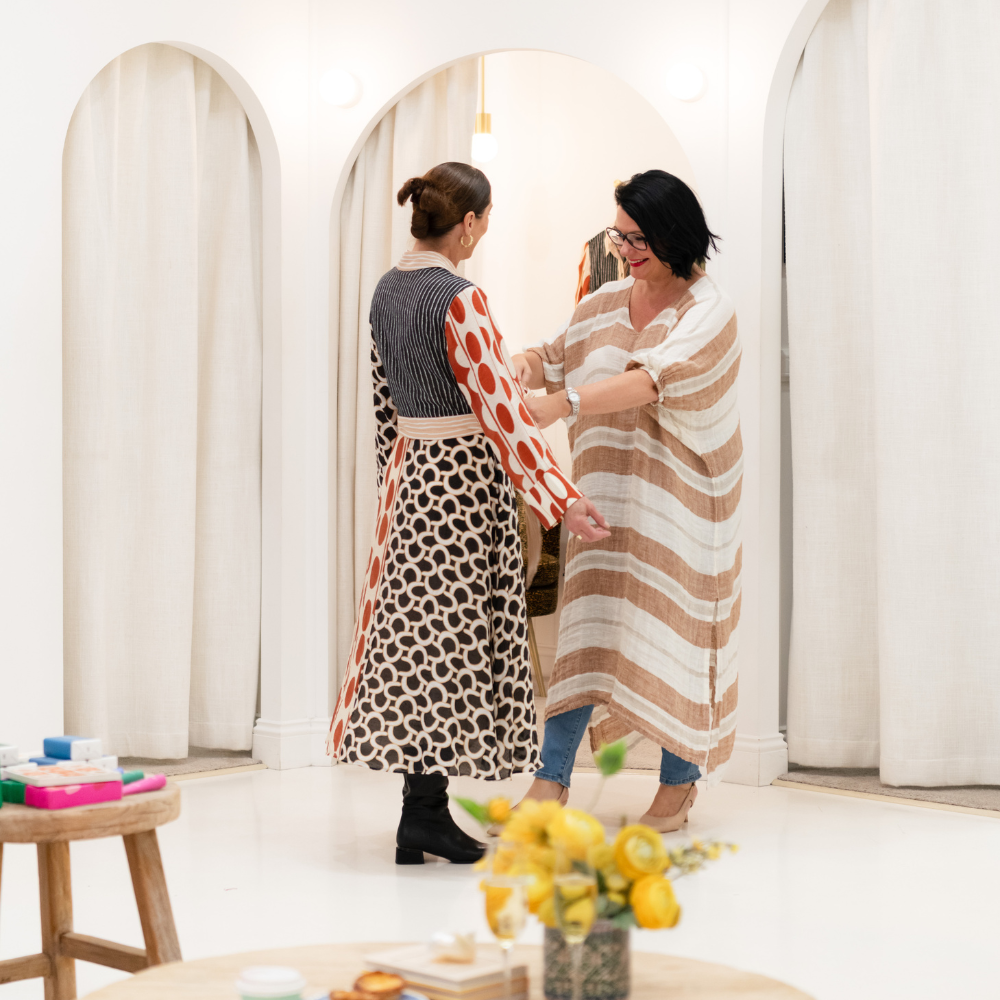Two brunette women trying on a dress in the Blue Bungalow store.