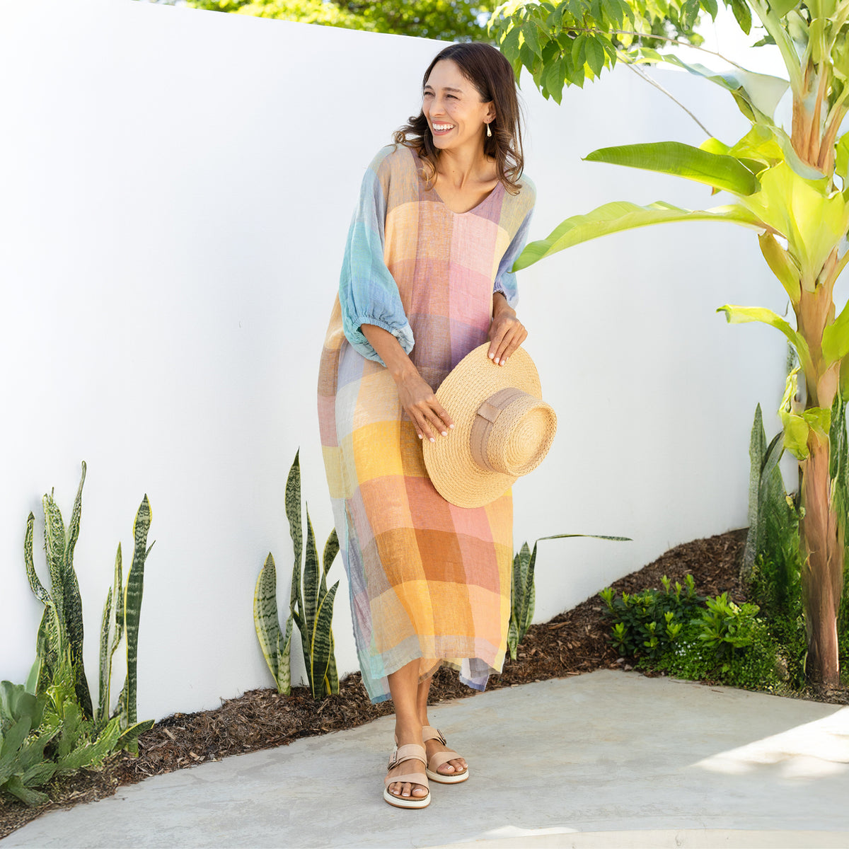 Brunette woman in a long flowy sherbet check billow sleeve resort dress