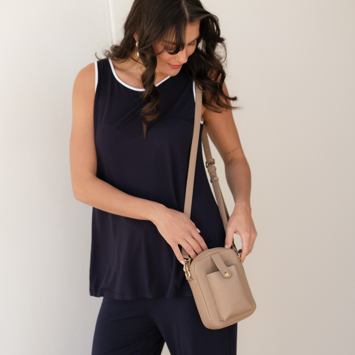 Brunette woman wearing a beige travel crossbody bag.