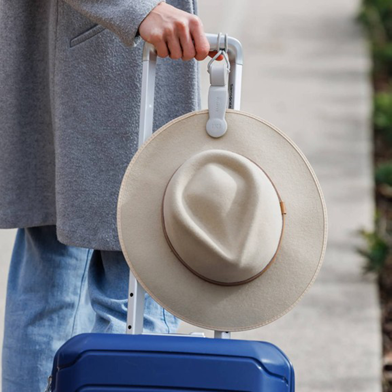 Wide-brim hat attached to a blue suitcase with a Klipsta hat clip.