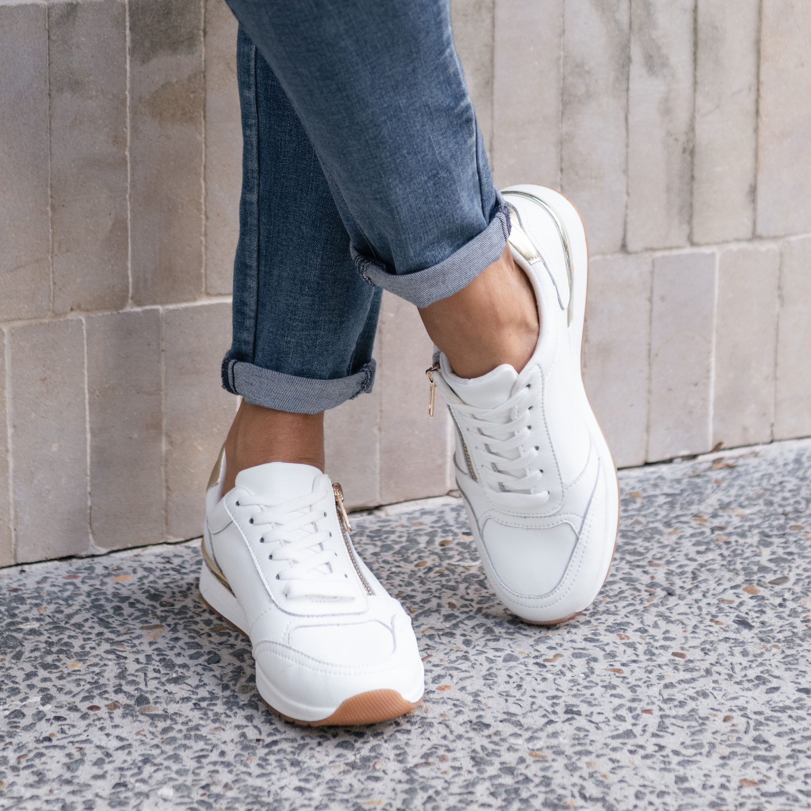 A close-up photo of a woman wearing white sneakers.
