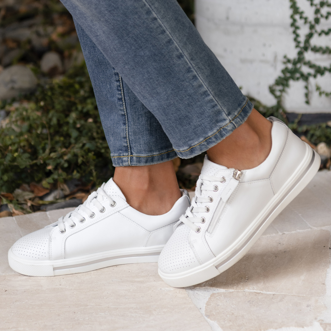 A close-up photo of a woman wearing white sneakers.