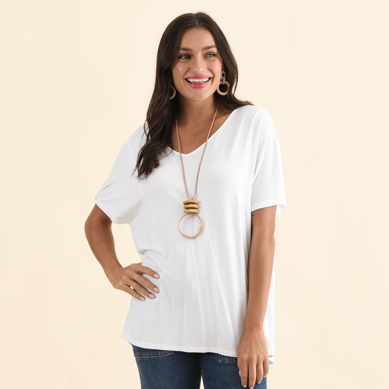 Brunette model wearing a draped white V neck tee.