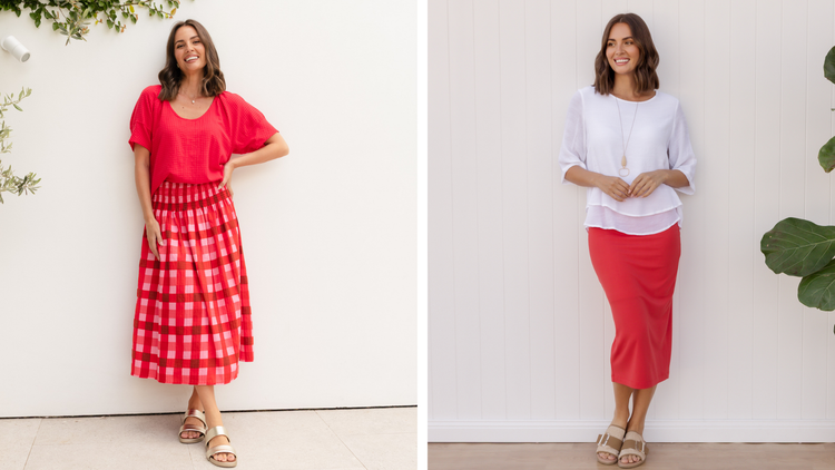 Two brunette women standing on a white wall with red midi skirts styled for all seasons.