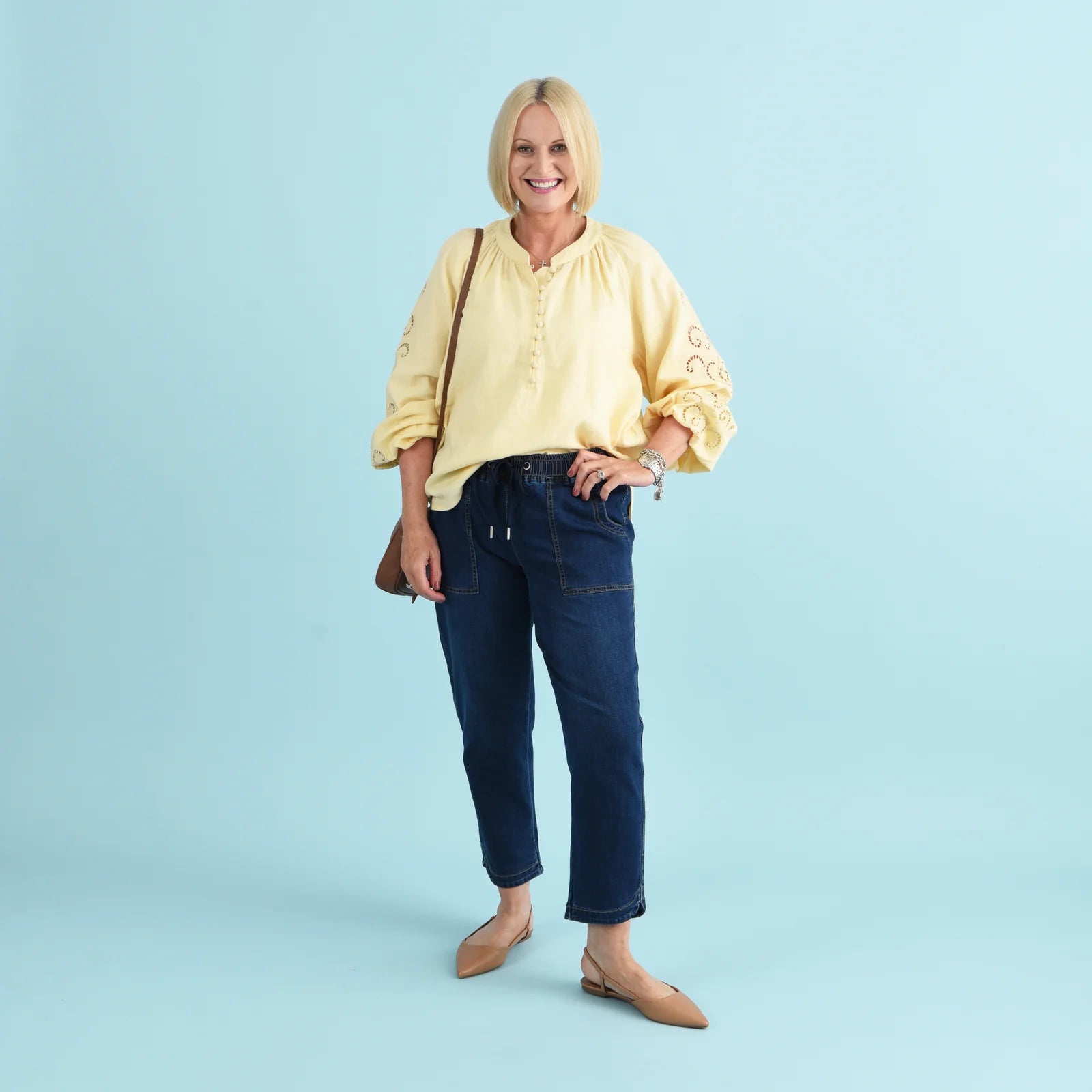 Blonde woman wearing blue denim jeans and a yellow blouse.