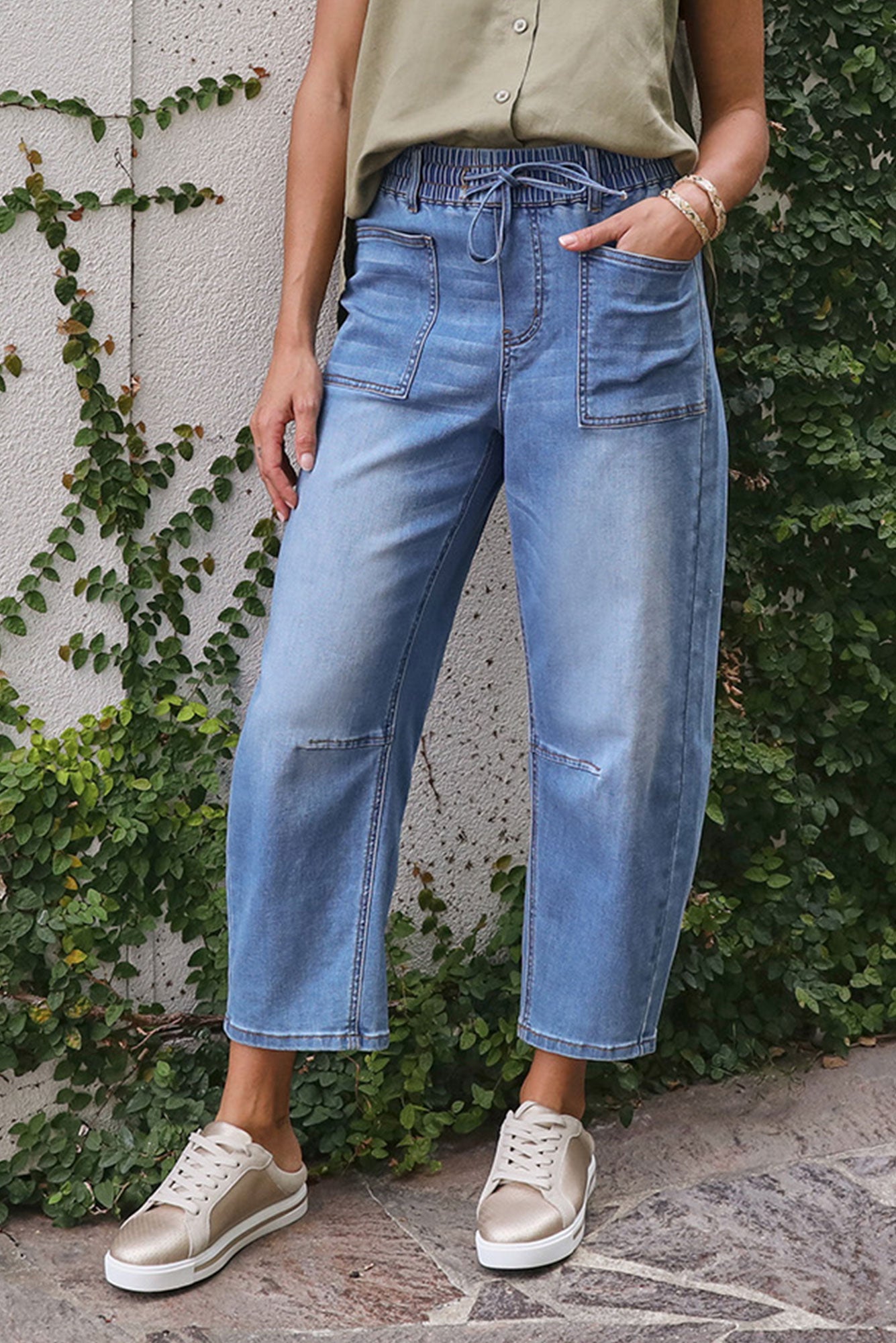 Woman wearing blue barrel jeans in a garden.