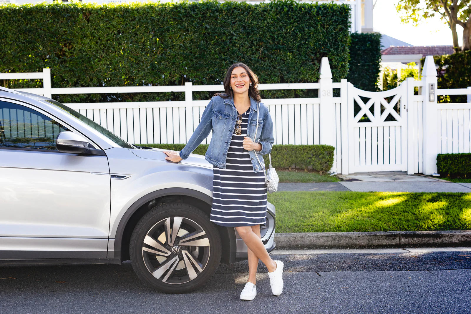 Brunette model leaning against a car in a road trip dress from Blue Bungalow