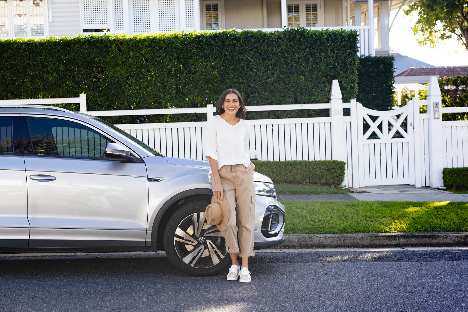 Brunette model wearing a comfortable road trip outfit in front of a car.