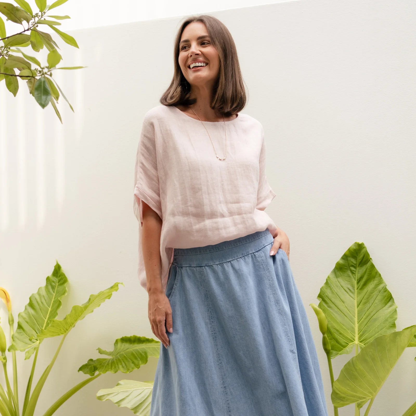 Brunette woman in a pink top standing in a garden.