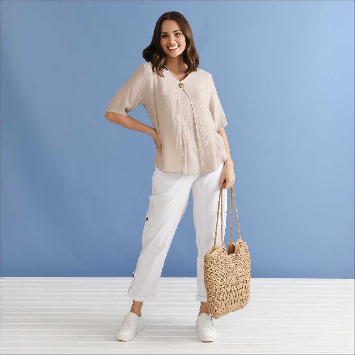 Brunette woman in a neutral top and white pants