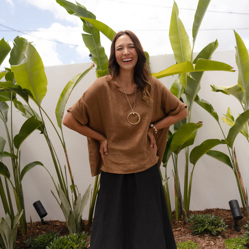 Brunette woman wearing a linen set in a tropical garden.