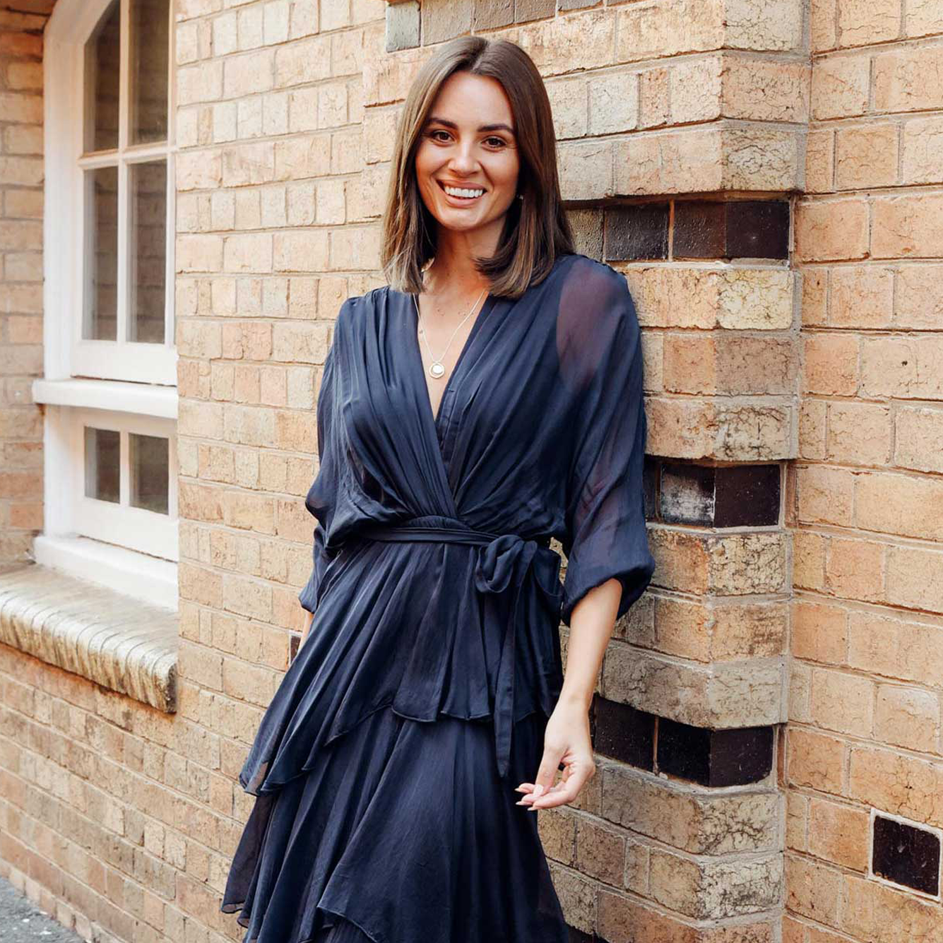 Brunette model wearing a navy silk event dress for a winter wedding. 