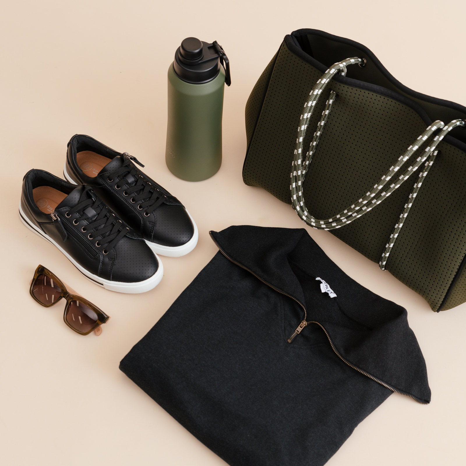 Black travel essentials: a bag, black sneakers, sunglasses and waterbottle.